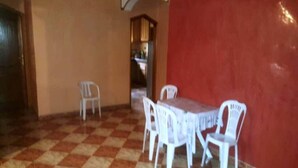 Un comedor con piso de tablones cuadriculados, sillas de plástico blanco y una mesa.