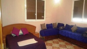 Una habitación con una cama, un sofá y una ventana con persianas.