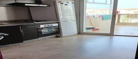 A kitchen with a gas stove, oven, and white refrigerator.