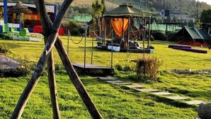 Ein Campingplatz mit Zelten, einer Reetdachhütte und einem Rasenfeld.