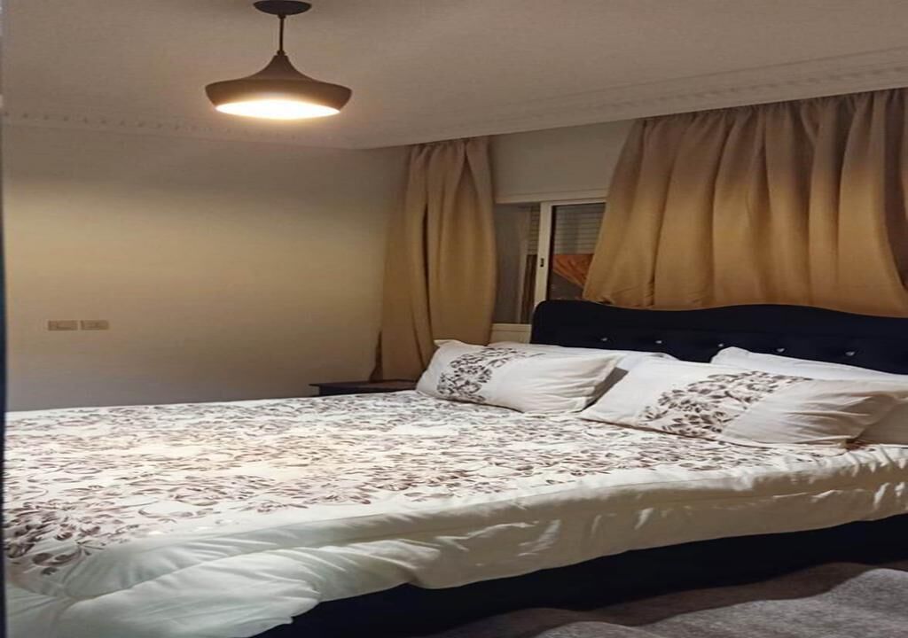 Un dormitorio con cama, cortinas y una lámpara en el techo.
