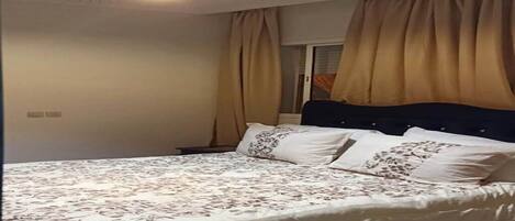 Un dormitorio con cama, cortinas y una lámpara en el techo.