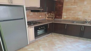A kitchen with a refrigerator, stove, oven, and sink. - Pleasant apartment in Jawharat Mogador 4729 (Essaouira)