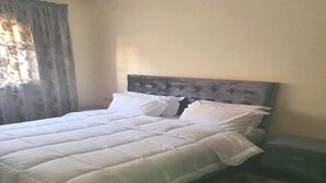 A neatly made bed with a grey headboard, a white duvet, and several pillows. - Pleasant apartment in Jawharat Mogador 4729 (Essaouira)