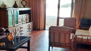 Ein Wohnzimmer mit einer Couch, einem Holzstuhl, einem Couchtisch und einer Vitrine mit Glastüren.
