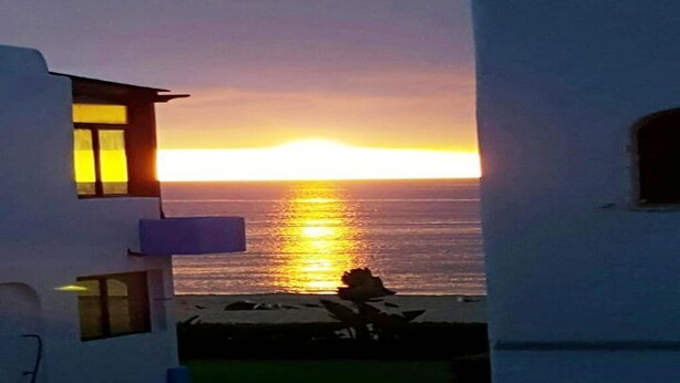 Ein Gebäude mit Blick auf den Sonnenuntergang über dem Meer.