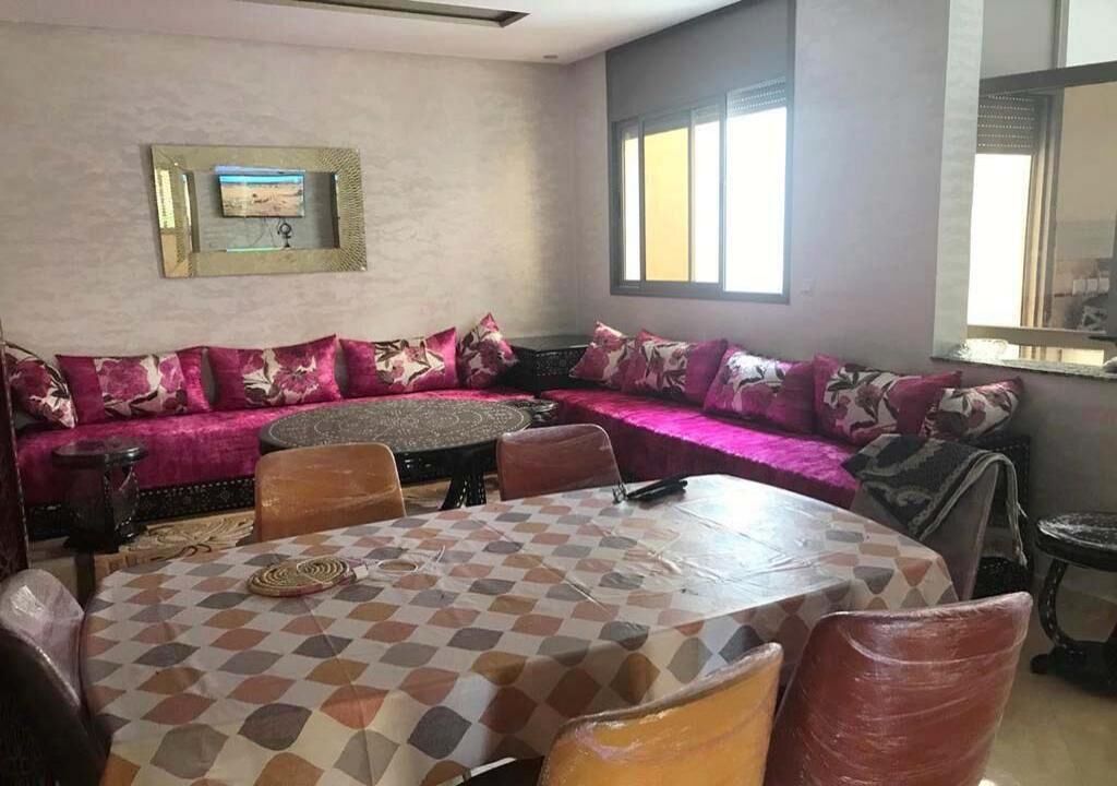 A dining area with a checkered table, a sofa with patterned cushions, and a wall-mounted picture frame.