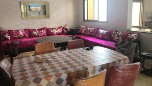 A dining area with a checkered table, a sofa with patterned cushions, and a wall-mounted picture frame.