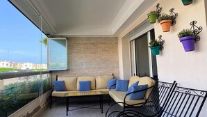 Un balcón con un sofá, una silla y plantas en macetas.