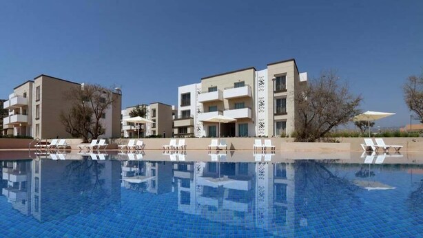 Un hôtel moderne doté d’une piscine, de nombreux balcons et de chaises longues.