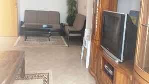 Un salon comprenant un canapé, une table basse, un téléviseur et un meuble.
