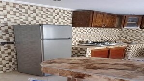 Una cocina con refrigerador, estufa y salpicadero de azulejos.