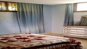 Un dormitorio con cama, cortinas, cómoda y ventana.