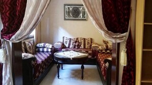 Una habitación con un conjunto de sofás, una mesita redonda y un adorno en la pared.