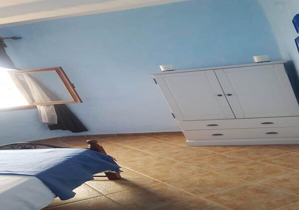 A bedroom with a bed, a wardrobe, and a window.