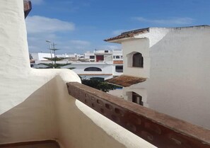 Vue d’un quartier résidentiel avec des bâtiments blancs et un balcon doté d’une balustrade marron.
