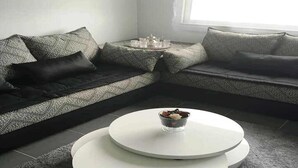 Una sala de estar moderna con un sofá modular, dos mesas redondas para café y una mesita con una bandeja de objetos.