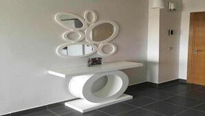 Un interior moderno con una consola blanca, un espejo decorativo y un elemento de iluminación.