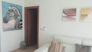 Una sala de estar con un sofá blanco, un cuadro de cebra y dos cuadros enmarcados en la pared.