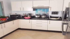 A modern kitchen with white cabinets, a microwave, stove, and various cooking utensils.