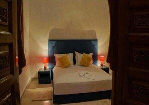 A bedroom with a large bed, two bedside tables with lamps, and a wooden headboard.