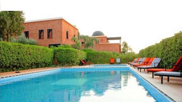 A swimming pool with lounge chairs and a building with a dome in the background. - Sublime villa with swimming pool in Marrakech 4814 (Marrakech)