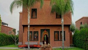 A building with a symmetrical facade, two palm trees, and a central fountain. - Sublime villa with swimming pool in Marrakech 4814 (Marrakech)