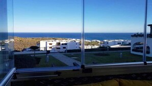A modern building with large windows offering a view of the sea and a coastal town. - Nice apartment in Bella Vista 4815 (Cabo Negro)