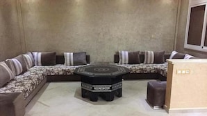 A living room with a sofa set, a coffee table, and a small ottoman. - Villa (Saidia)