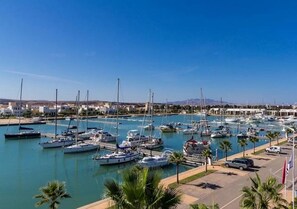 A marina with multiple boats docked, a parking area, and a clear blue sky. - Villa (Saidia)
