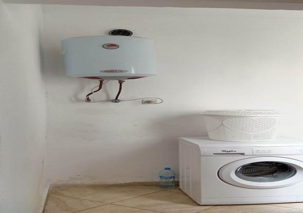 A laundry area with a wall-mounted water heater, a washing machine, and a water dispenser.