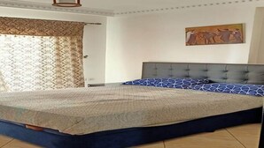 Ein Schlafzimmer mit Bett, Kopfstütze, einem Gemälde und einem Fenster mit Vorhängen.