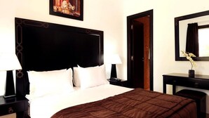 A hotel room with a large bed, two bedside tables, a nightstand, a dresser, and a mirror. - Arz Village Farah Inn 4832 (Ifrane)