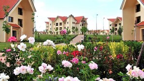 Un complesso residenziale con diversi edifici, un percorso centrale e un giardino curato con diverse fioriture.