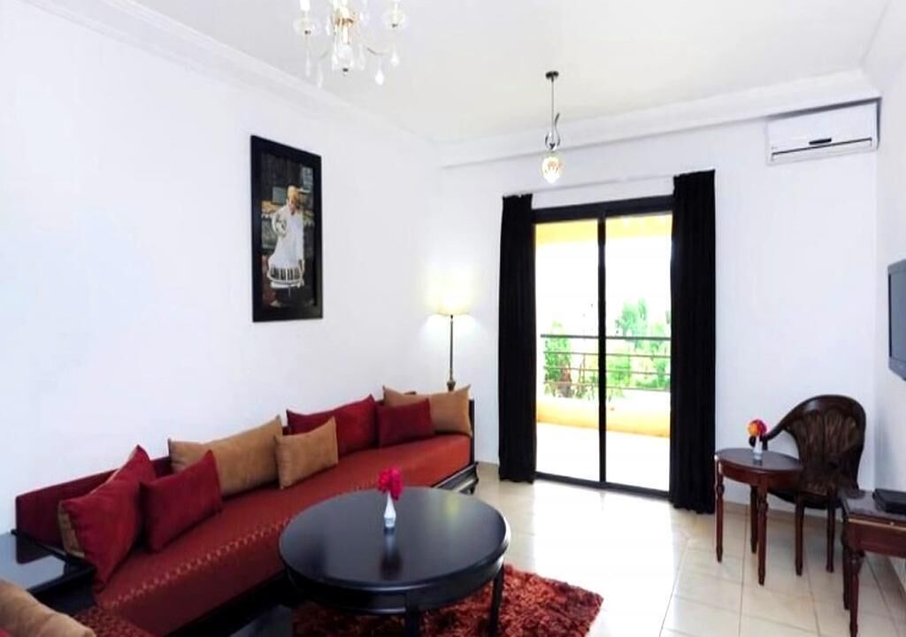 A modern living room with a red sofa, a round coffee table, and a TV on a stand.