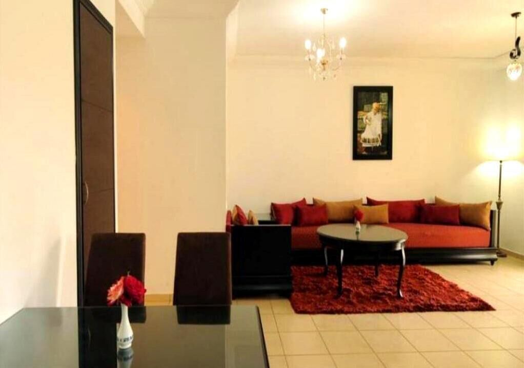 A living room with a black table, red sofa, and a red rug.