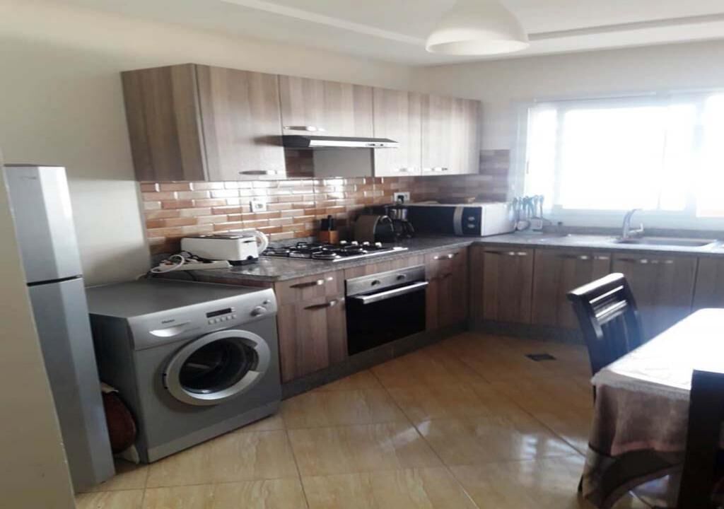 Una cocina moderna con electrodomésticos integrados, armarios de madera y un amplio ventanal que proporciona luz natural.