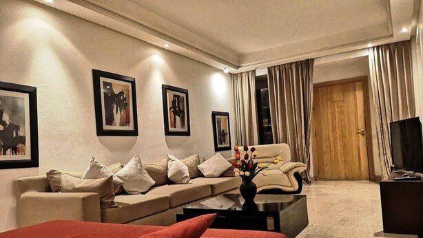 A modern living room with a sofa, a red bed, and a coffee table. - Generosa Residence 4855 (Marrakech)