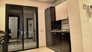 A compact kitchen with a refrigerator, microwave, and a sliding glass door leading to a balcony. - Generosa Residence 4855 (Marrakech)