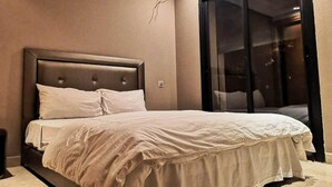 A bedroom with a large bed, a headboard, and a sliding glass door leading to a balcony. - Generosa Residence 4855 (Marrakech)