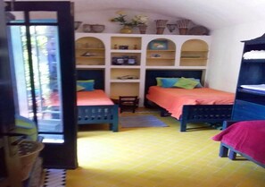 A room with two beds, a window, and shelves with various items.