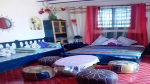 Un dormitorio con cama, almohadas, mesita de noche, lámpara, espejo y ventana con cortinas.