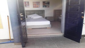 Un dormitorio con cama, mesita de noche y estante en la pared.