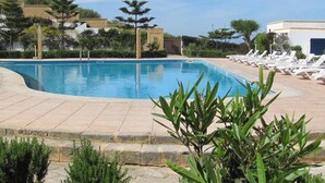 Una piscina con sillas de descanso y un edificio al fondo.