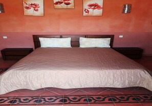 A bedroom with a large bed, two bedside tables, and three wall-mounted flower paintings.