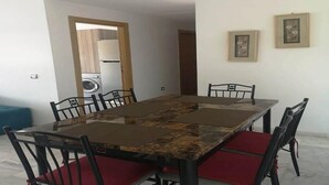 Un comedor con una mesa rectangular, seis sillas y un banco tapizado en rojo.