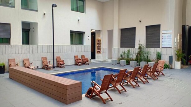 Un área de piscina con sillones de descanso y una terraza de madera.