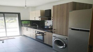 Una cocina moderna con lavadora y secadora integradas, estufa a gas y refrigerador.
