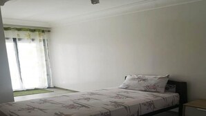 Una cama individual con ropa de cama floral, una mesita de noche y una ventana con cortinas.