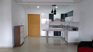 A modern kitchen with white cabinetry, a granite countertop, and a wooden door.